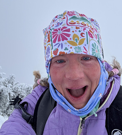 Woman smiling joyously in winter gear on a snowy day