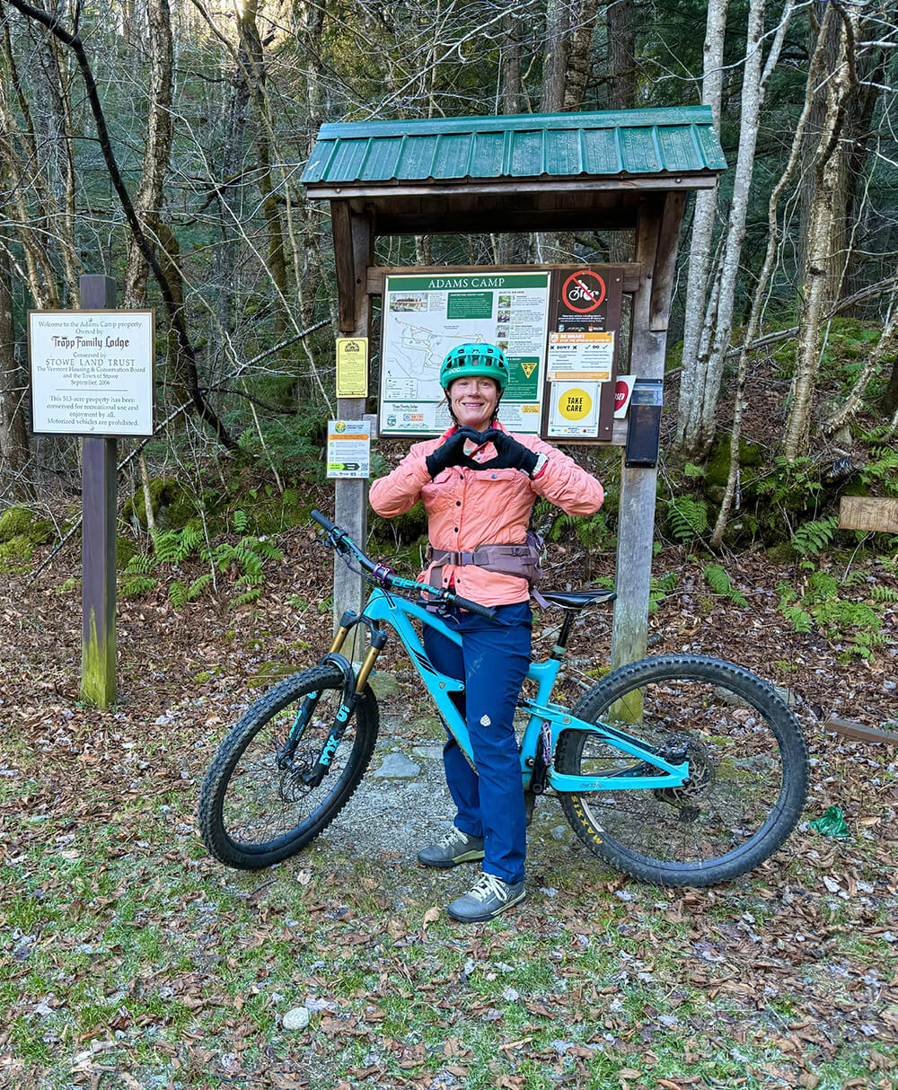 Woman making a heart with her fingers on a bike trail