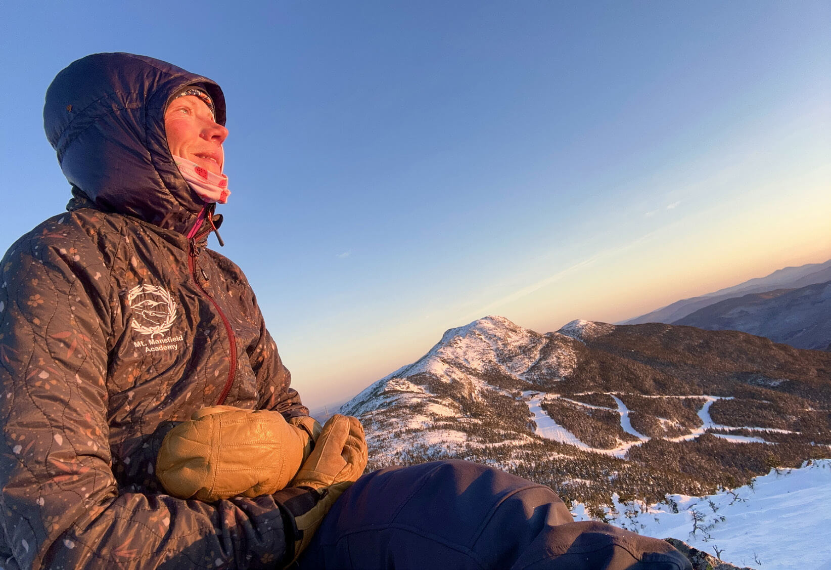 Woman sitting at the top of a mountain at sunrise
