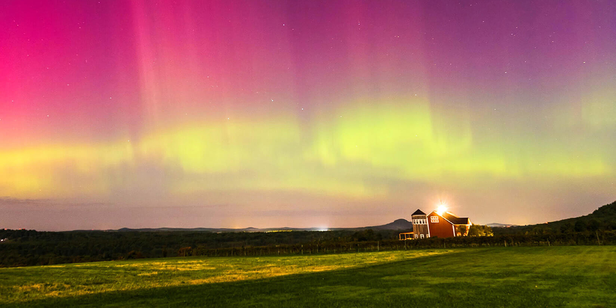 Northern lights dancing above a farm with a silo