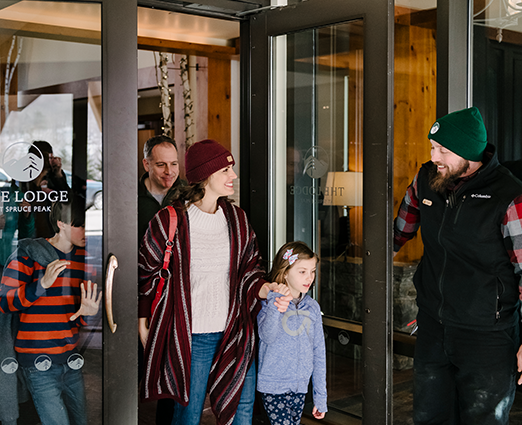 Valet employee holding door open for family in winter gear