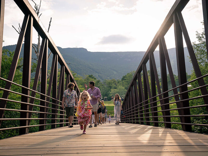 Families walking across a steel bridge in summer