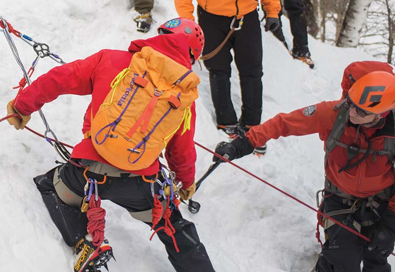 Men in snow climbing with rope