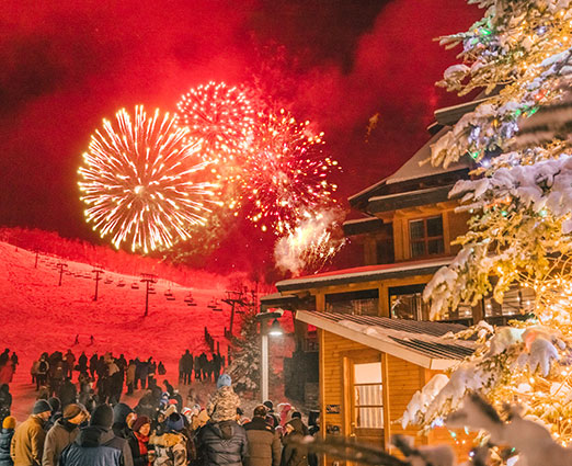 Fireworks over a ski mountain with a christmas tree in the foreground - The Lodge at Spruce Peak