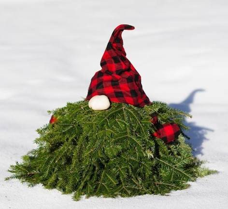 A short gnome made of pine branches sitting in the snow - The Lodge at Spruce Peak