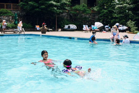 Kids swimming in a clear blue pool - The Lodge at Spruce Peak