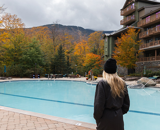 woman overlooking a hotel pool with fall mountains in the background
