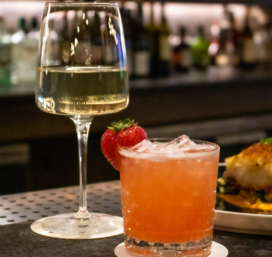 White wine and a signature cocktail with a strawberry garnish